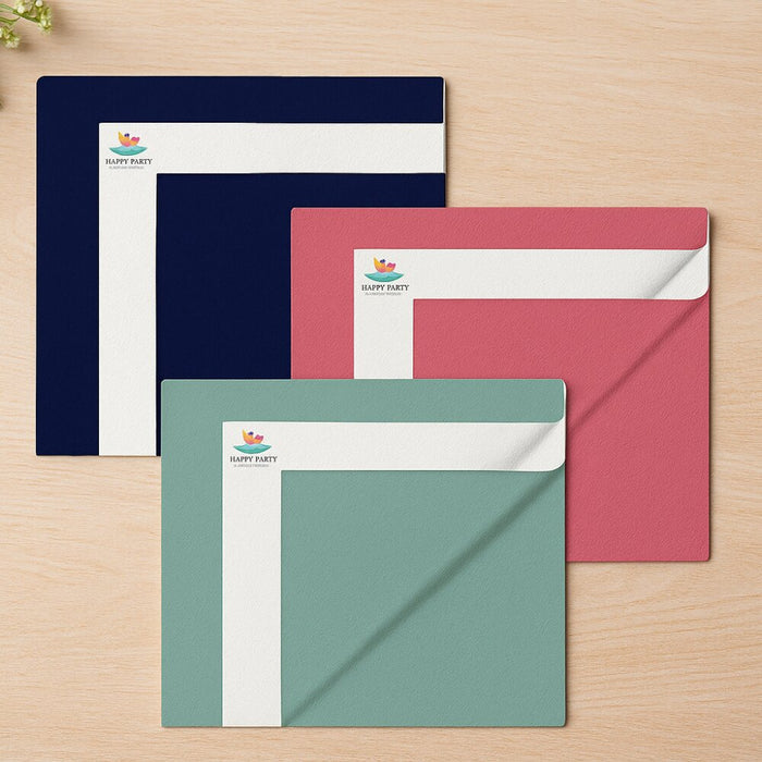 Three custom-printed paper envelopes in navy blue, dusty pink, and sage green, arranged in a fan shape on a light wood background. Each envelope features a white header strip printed with the logo 'Happy Party'.