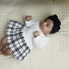 Baby lying on a Happy Matty zigzag print bed protector mat