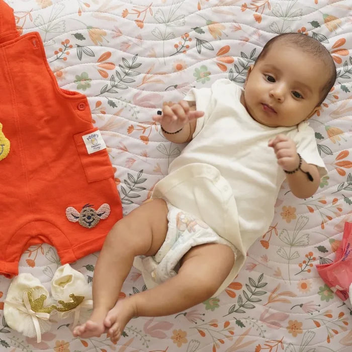 Baby lying on a Happy Matty leaves print bed protector mat