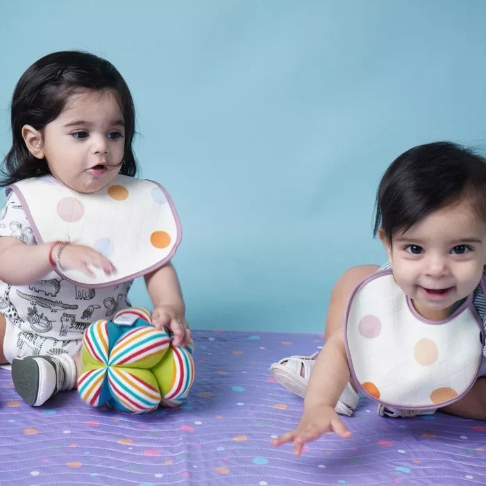 Baby lying on a Happy Matty polka dots print bed protector mat