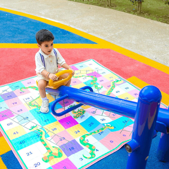Children playing snakes and ladders on the Happy Matty picnic mat