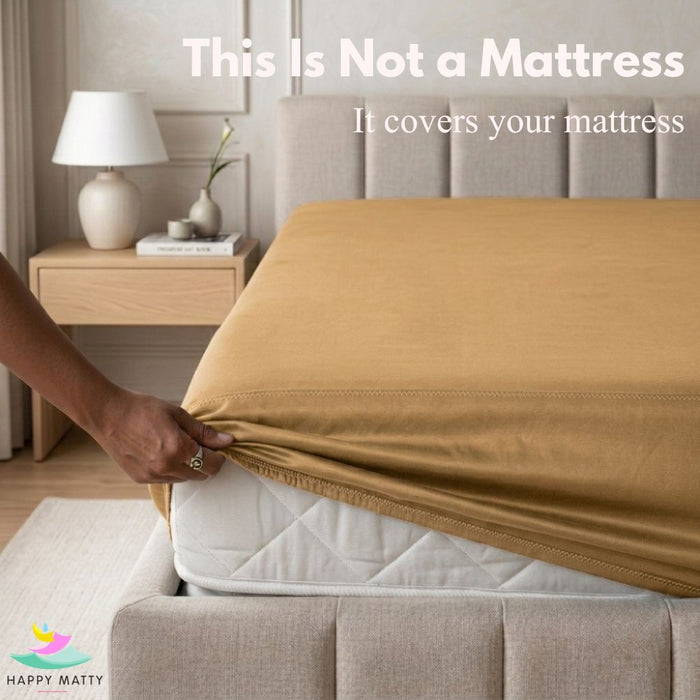 A person's hand is shown pulling a mustard yellow fitted sheet over a white mattress in a modern bedroom setting. White text at the top reads 'This Is Not a Mattress.