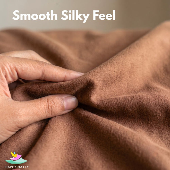 A close-up of a person's hand stretching and pulling a brown fabric to demonstrate its smooth, silky texture. White text at the top reads 'Smooth Silky Feel' and a 'Happy Matty' logo is visible in the bottom-left corner.