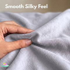 A close-up of a hand pulling and stretching a light gray plush fabric, with the text 'Smooth Silky Feel' at the top and a 'Happy Matty' logo in the bottom-left corner.