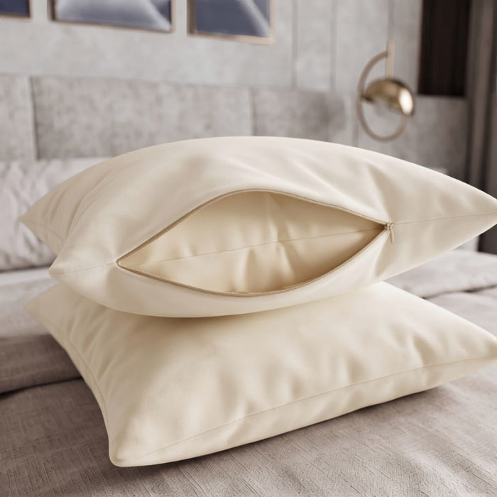Two cream-colored pillowcases stacked on a bed, with the top one slightly open to show the interior lining.