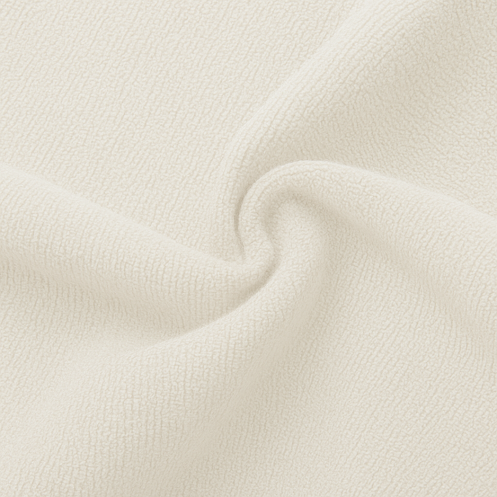 A close-up of textured cream-colored fabric with soft folds and a ribbed knit pattern.