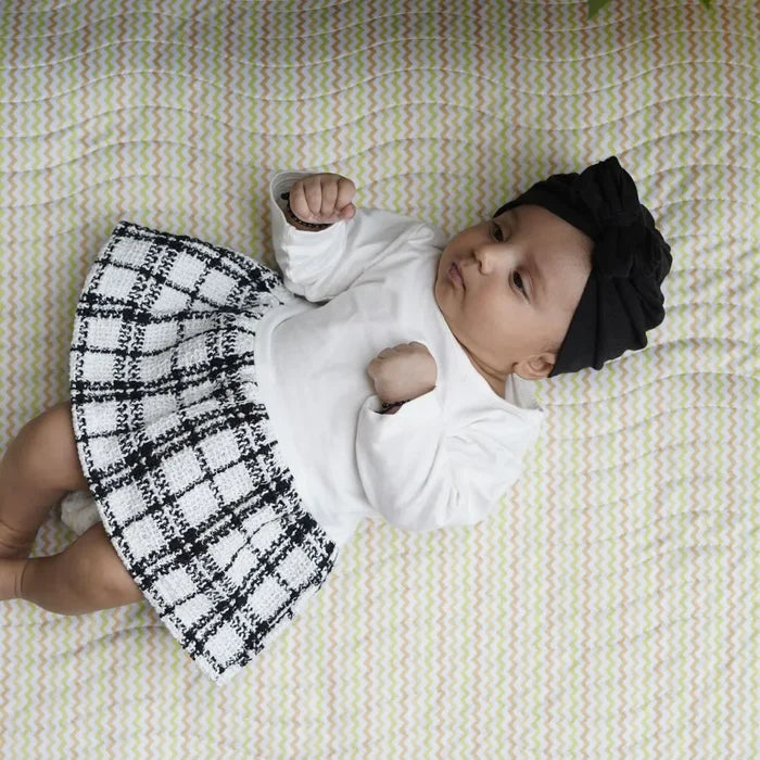 Baby lying on a Happy Matty zigzag print bed protector mat